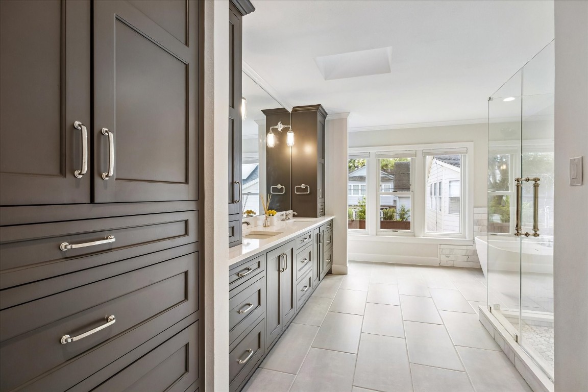 1925 Banks Street Houston, TX 77098 - Photo 20 of 38 This spacious and newly gutted primary bathroom features elegant cabinetry, a large double vanity, and ample natural light from a row of windows. A glass-enclosed shower adds a modern touch, complemented by sleek tile flooring.