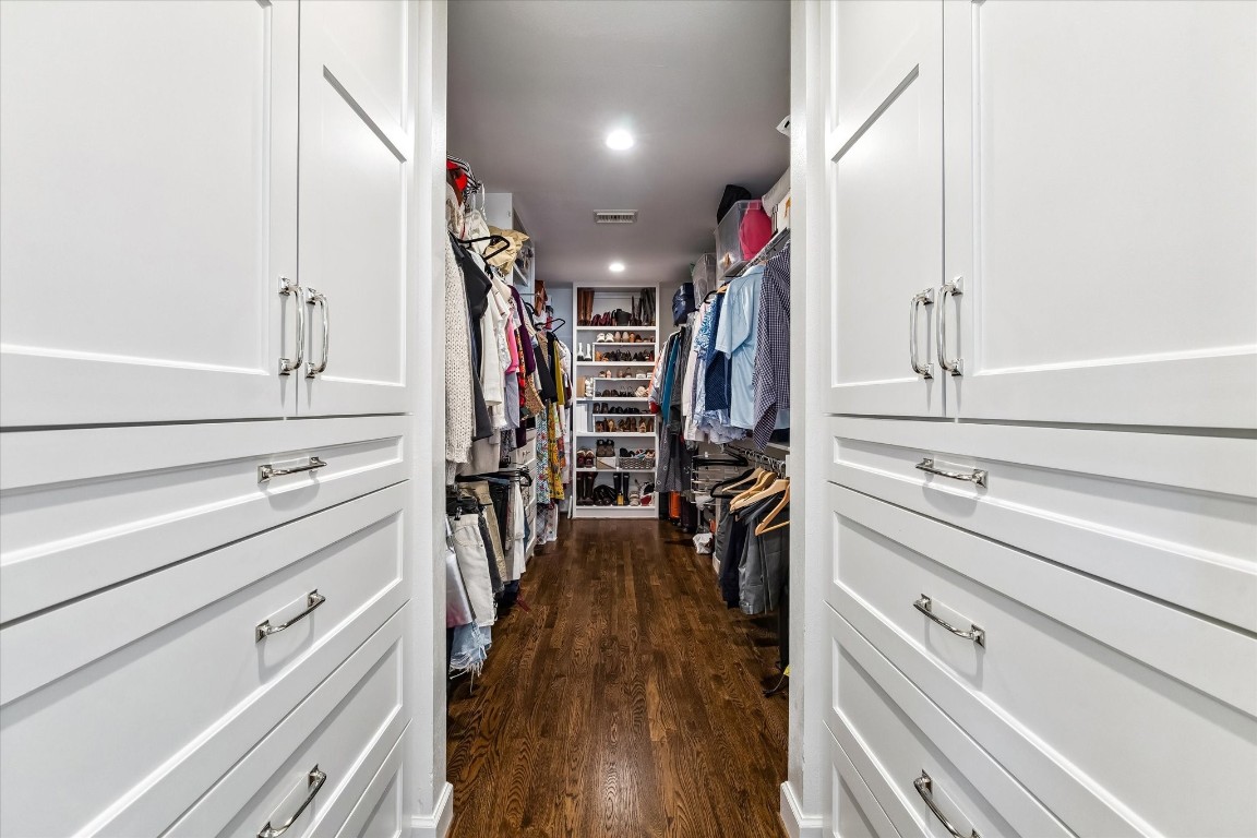 1925 Banks Street Houston, TX 77098 - Photo 23 of 38 A generous primary walk-in closet features sleek white cabinetry, ample hanging space, and elegant hardwood flooring. It's well-lit and organized, perfect for keeping your wardrobe tidy and accessible.