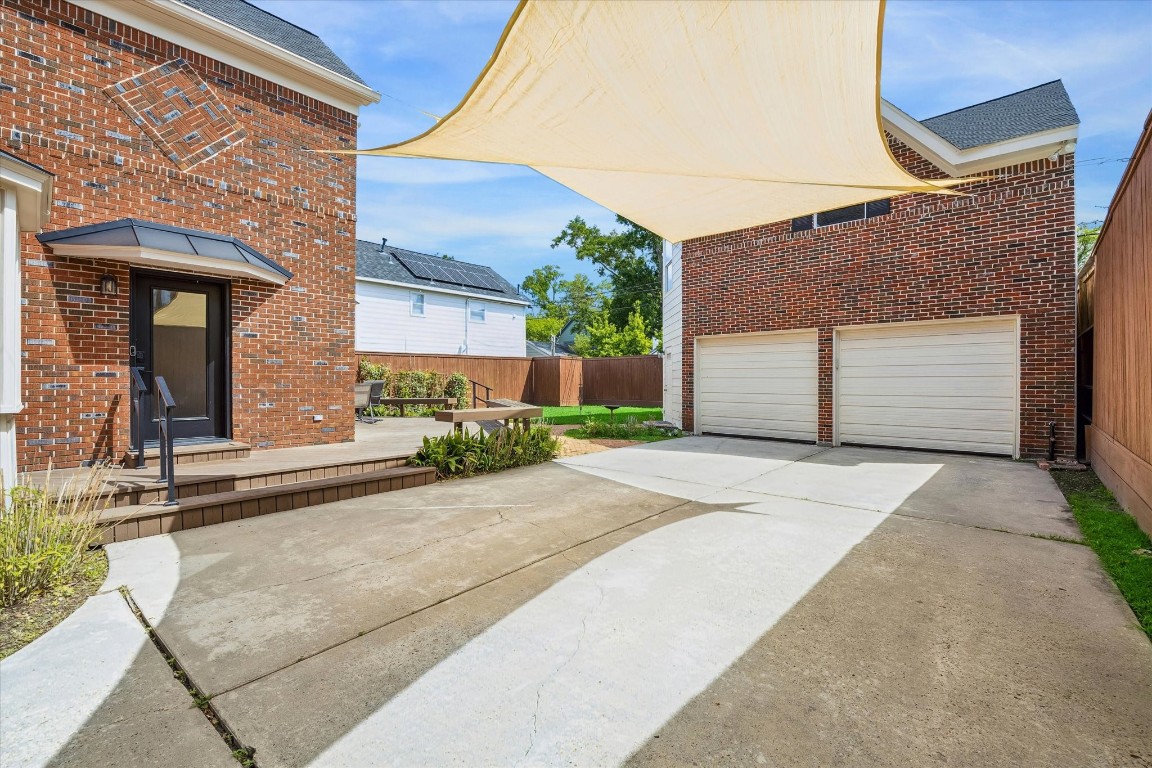 1925 Banks Street Houston, TX 77098 - Photo 34 of 38 This photo shows a spacious driveway with a dual garage and a brick exterior. There's a shade sail overhead and a small landscaped area near the entryway, creating a welcoming and functional outdoor space. Canopies can be removed.