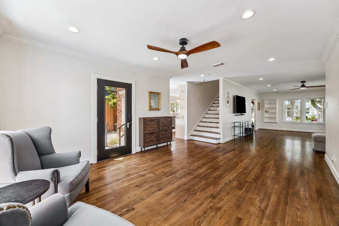 1925 Banks Street Houston, TX 77098 - Photo 10 of 38 This bright, open-concept living area features hardwood floors, recessed lighting, and a ceiling fan. A modern new black Pella door offers outdoor access, while a staircase leads to the upper level. The room includes built-in shelving and ample space for seating and entertainment.