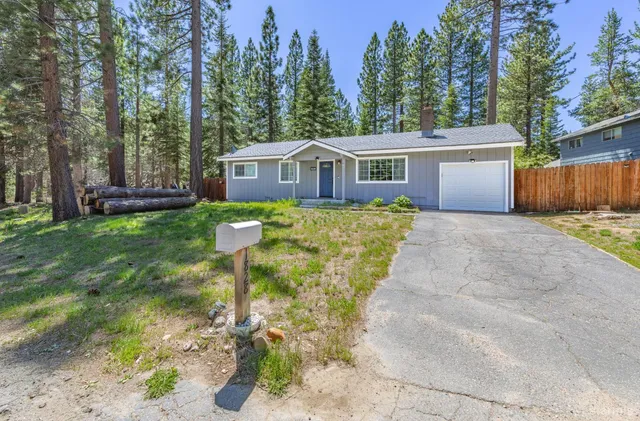 a front view of a house with a garden and trees