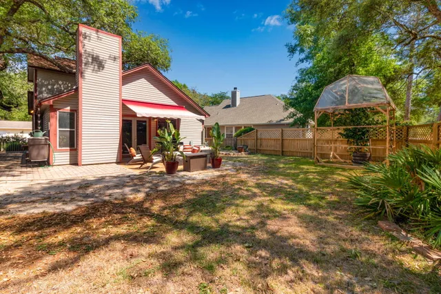 a backyard of a house with table and chairs under an umbrella