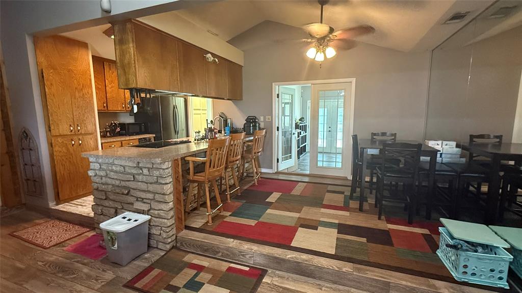 1356 Kerry Lane Azle, TX 76020 - Photo 8 of 27 Kitchen with stone-clad breakfast bar, wood-finish flooring, and vaulted ceiling