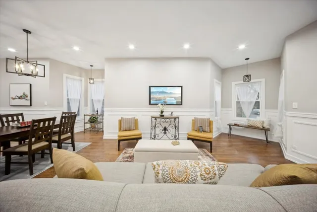 a living room with furniture kitchen view and a chandelier