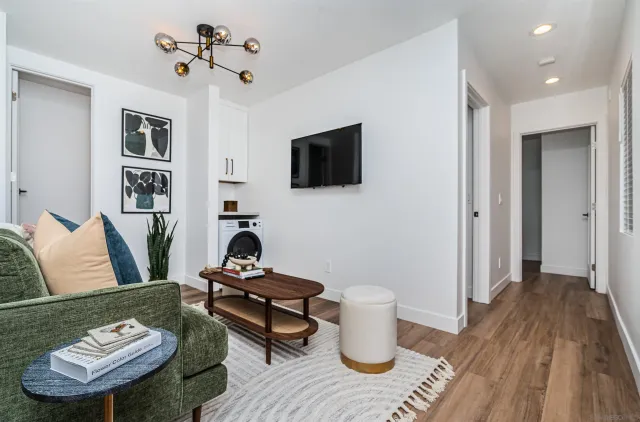 a living room with furniture a flat screen tv and kitchen view