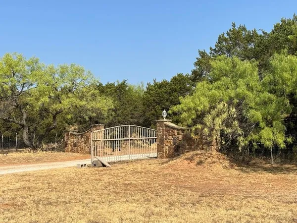 a view of a wooden house with a small yard and large trees