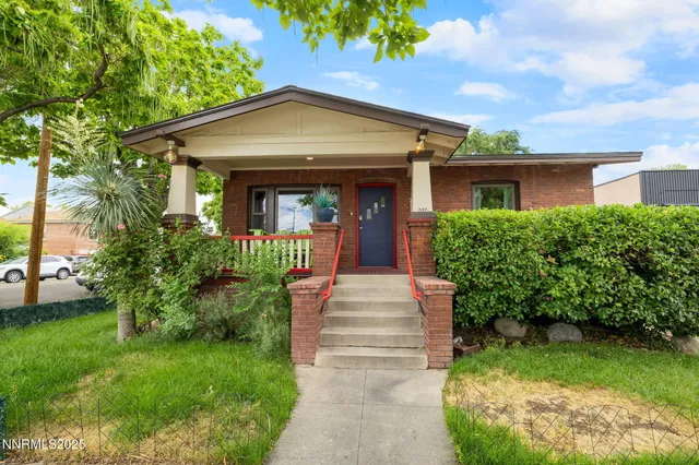 a front view of a house with a yard and potted plants