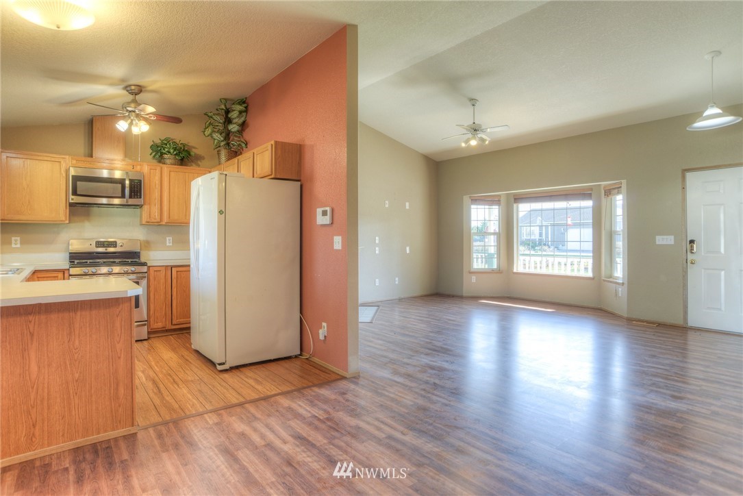 9320 181st Way Southwest Rochester, WA 98579 - Photo 11 of 21 a view of a kitchen with a refrigerator wooden floor and a window