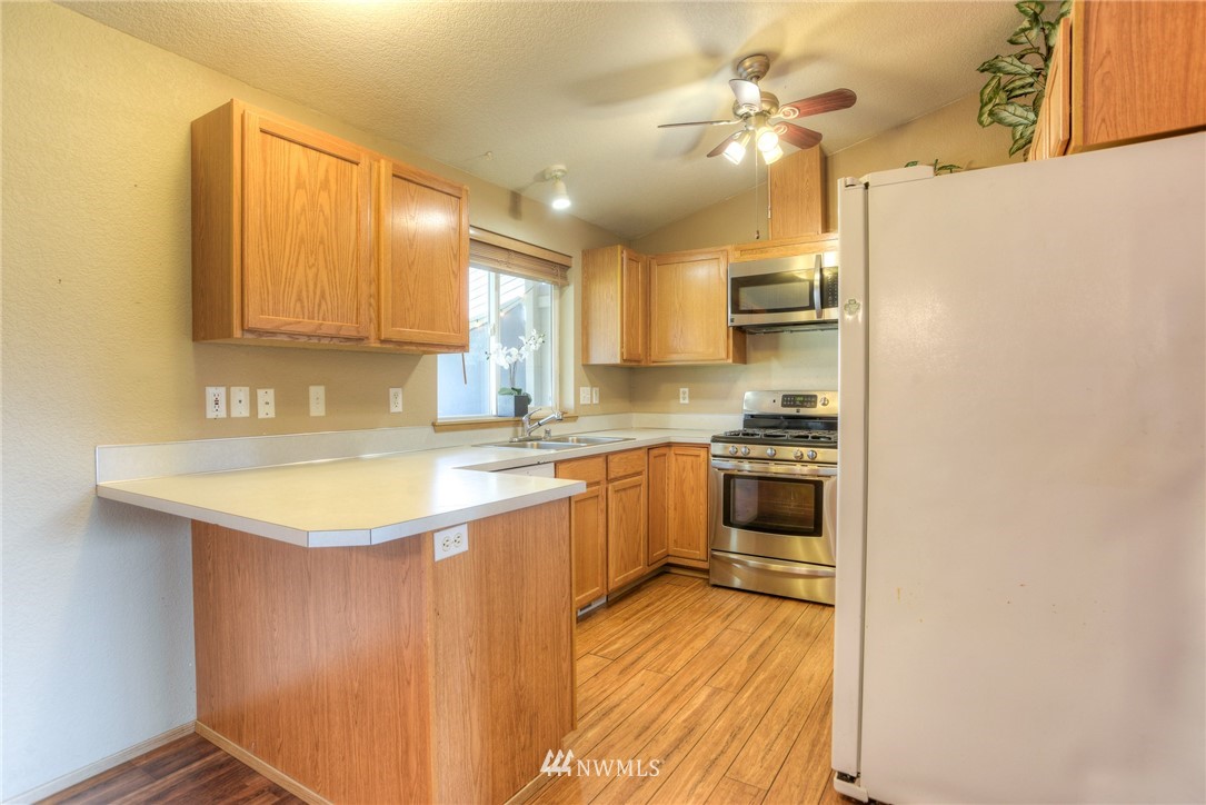 9320 181st Way Southwest Rochester, WA 98579 - Photo 9 of 21 a kitchen with stainless steel appliances granite countertop a sink a stove a refrigerator with grey cabinets