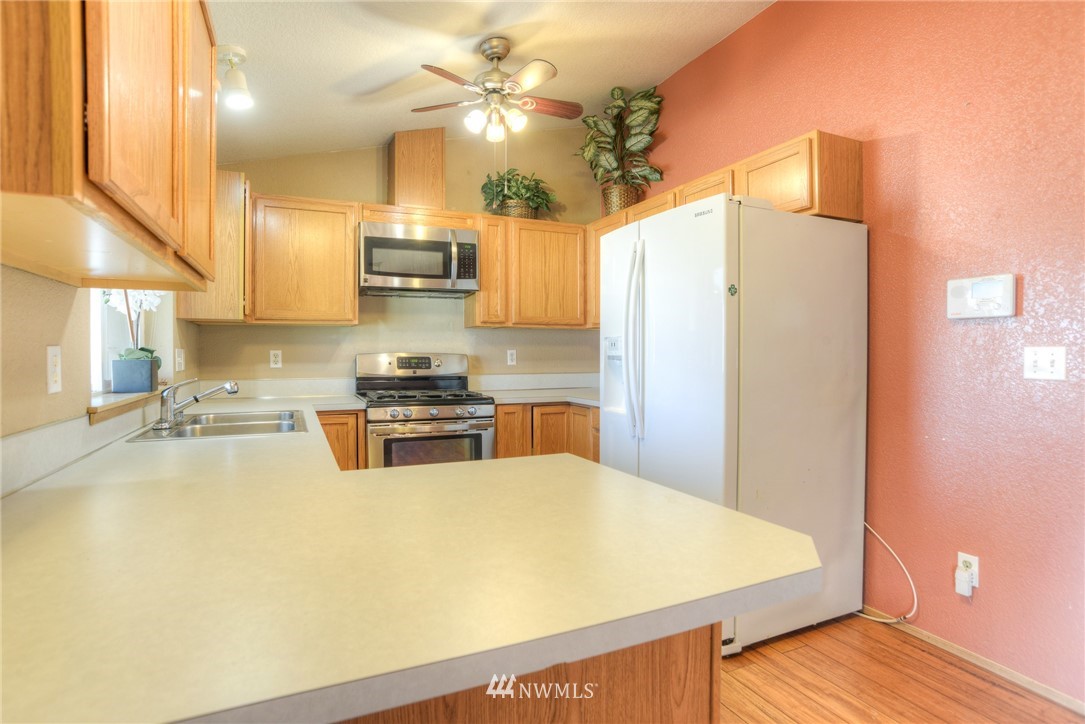 9320 181st Way Southwest Rochester, WA 98579 - Photo 10 of 21 a kitchen with stainless steel appliances a stove a refrigerator a sink a dining table and chairs with wooden floor