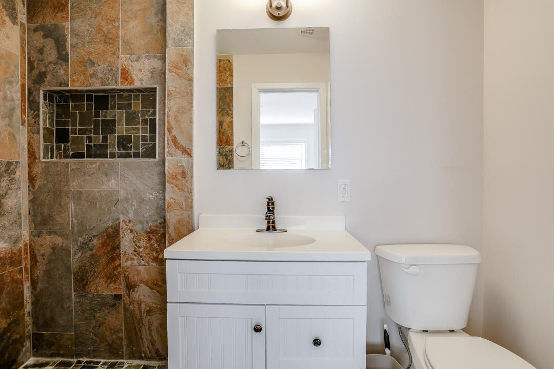 2123 66th Street Lubbock, TX 79412 - Photo 11 of 16 a bathroom with a toilet a sink and mirror