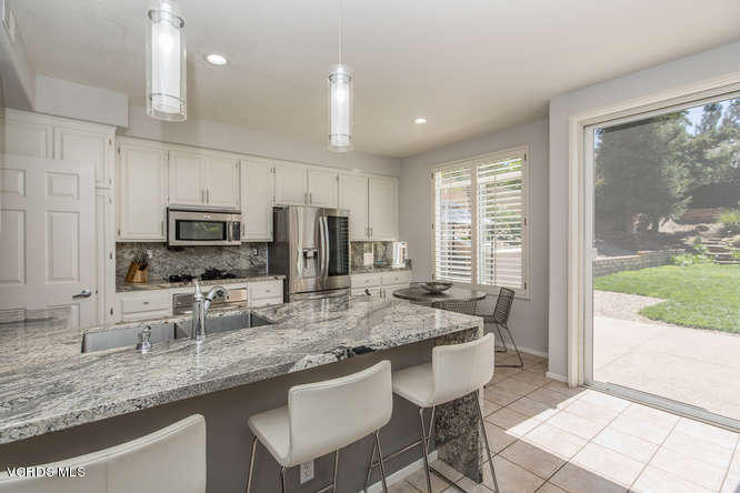 11218 Shadyridge Road Moorpark, CA 93021 - Photo 21 of 48 a kitchen with stainless steel appliances granite countertop a stove a sink a refrigerator a sink and white cabinets with wooden floor