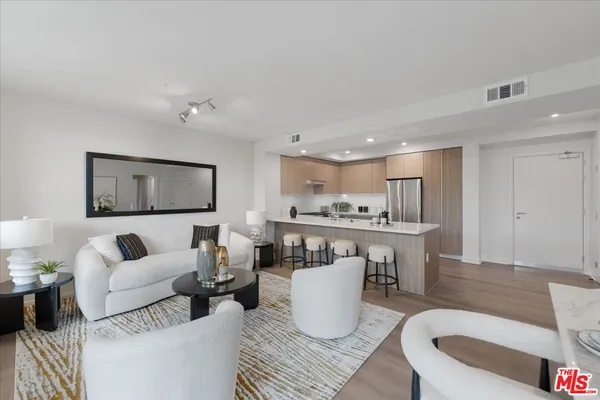 a living room with furniture a wooden floor and kitchen view
