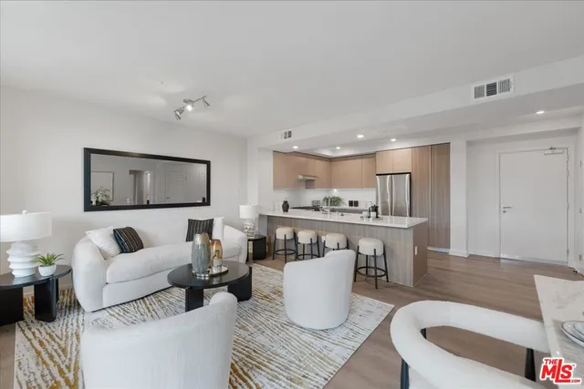 a living room with furniture a wooden floor and kitchen view