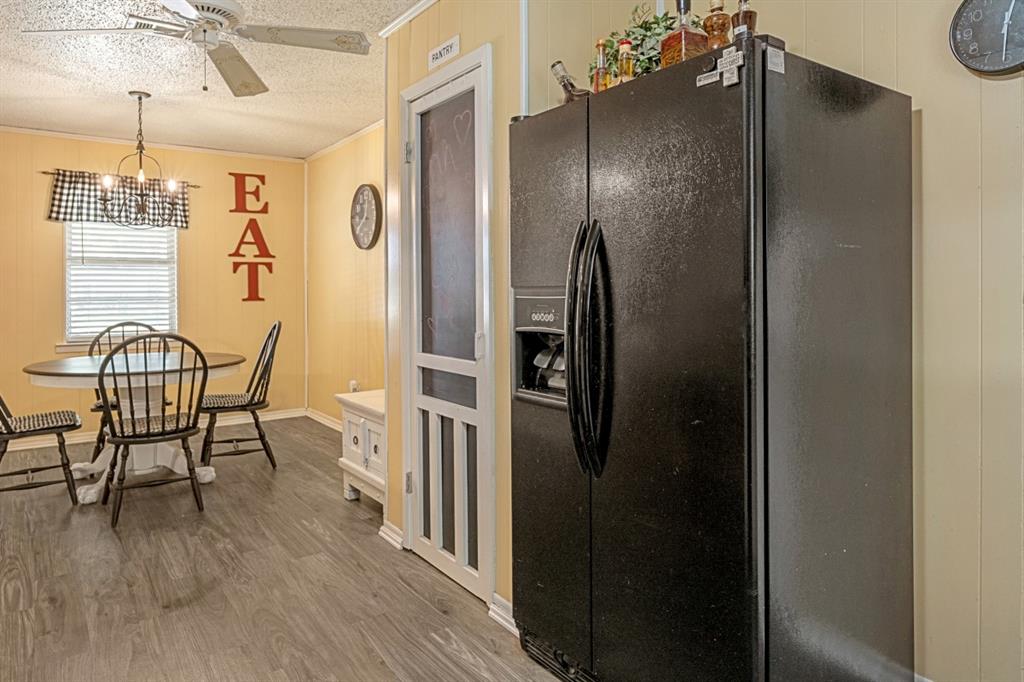 508 West 9th Street Kemp, TX 75143 - Photo 12 of 32 a kitchen with stainless steel appliances a refrigerator a stove a dining table and chairs with wooden floor