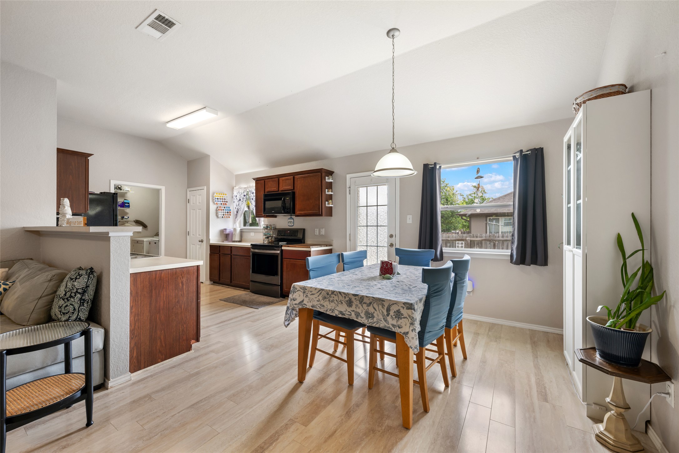 An inviting eat-in kitchen with vaulted ceilings and wood plank flooring connects seamlessly to a bright dining area.