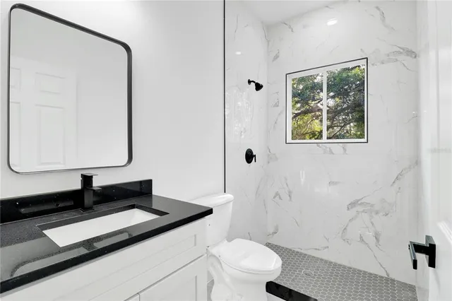 a bathroom with a granite countertop sink toilet and mirror