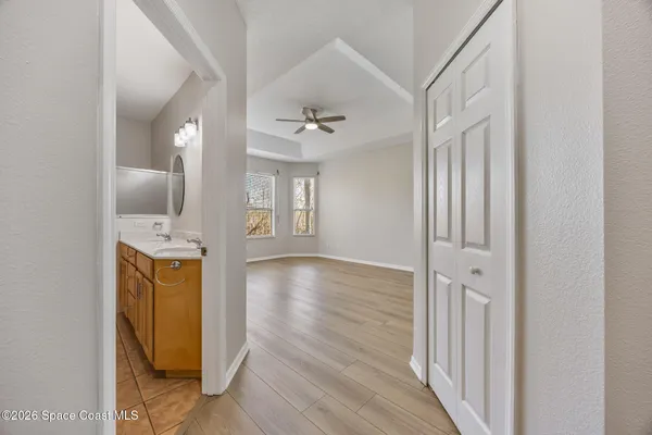 a view of a hallway with wooden floor and a bathroom