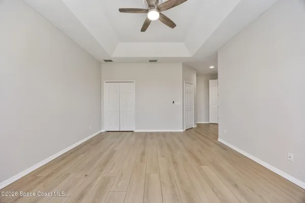an empty room with a ceiling fan and wooden floor