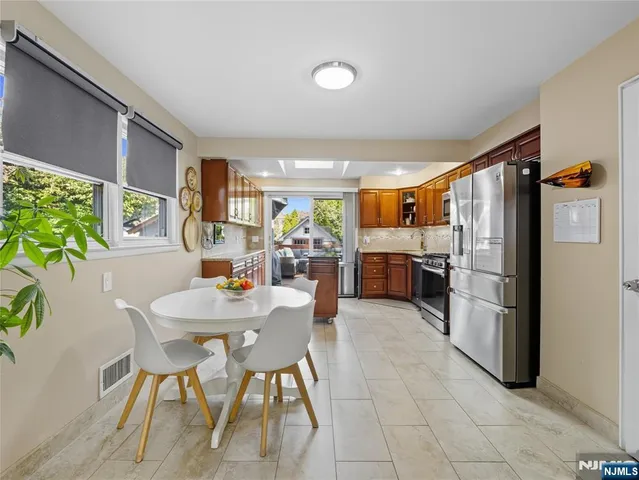 a kitchen with stainless steel appliances kitchen island granite countertop a refrigerator and a dining table