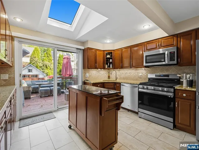 a kitchen with stainless steel appliances granite countertop a stove top oven a sink a counter space and cabinets