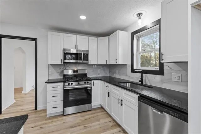 a kitchen with granite countertop white cabinets and appliances