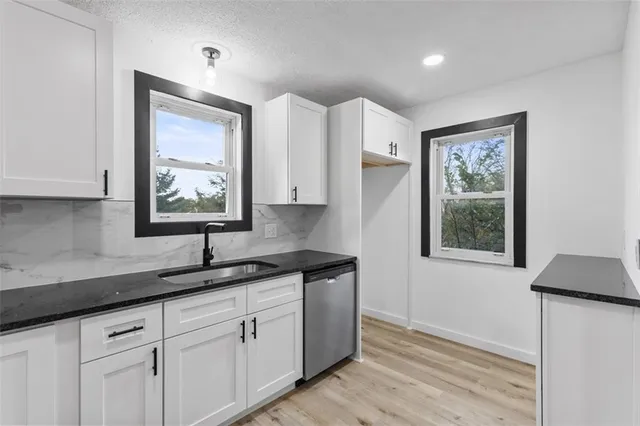 a kitchen with granite countertop white cabinets and window