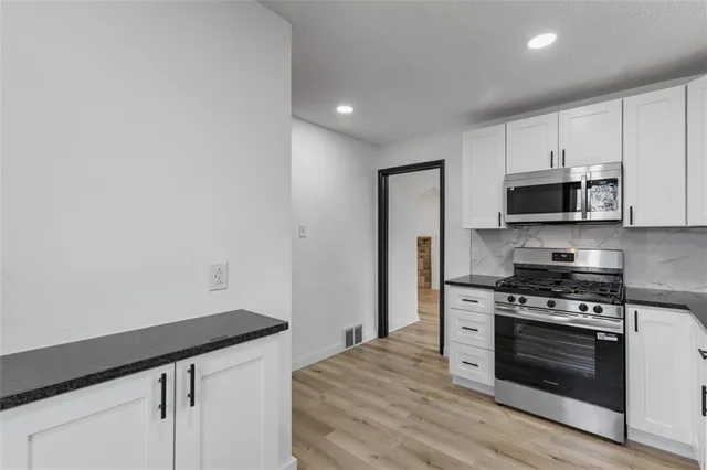a kitchen with granite countertop white cabinets and stainless steel appliances