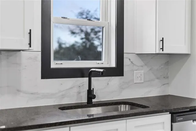 a kitchen with granite countertop white cabinets and a sink
