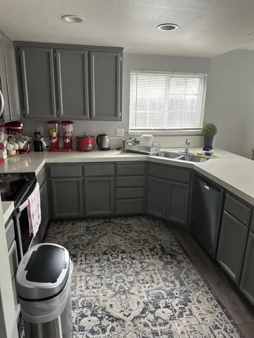 a kitchen with a sink a stove a refrigerator cabinets and a window