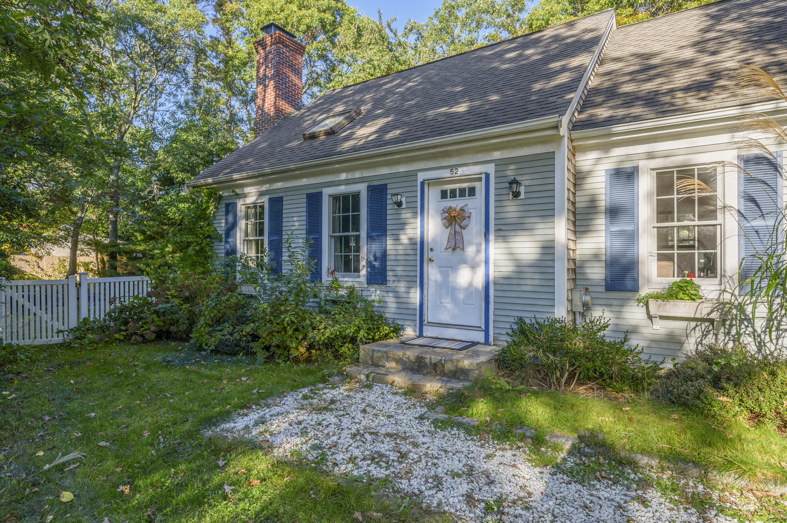 52 Zeno Crocker Road Centerville, MA 02632 - Photo 2 of 20 a view of a house with brick walls and a yard with plants and large tree
