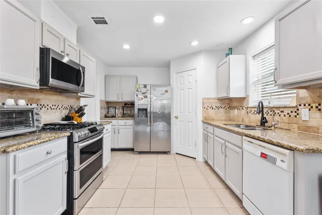 a kitchen with stainless steel appliances granite countertop a stove a refrigerator and a microwave