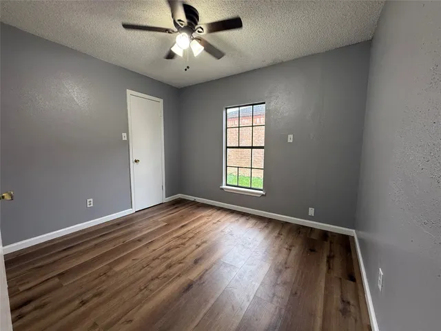 an empty room with wooden floor chandelier fan and windows