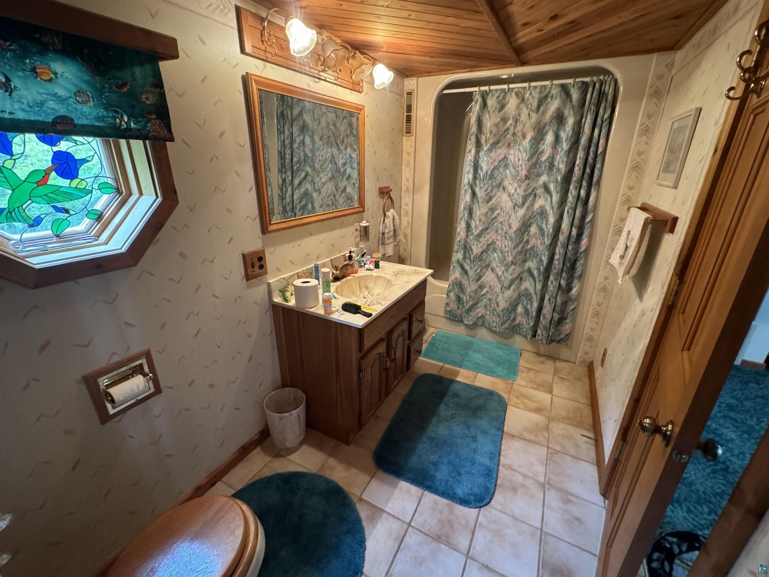 10690 Cedar Crest Road Iron River, WI 54847 - Photo 12 of 24 Bathroom featuring tile flooring, wood ceiling, toilet, and vanity with extensive cabinet space
