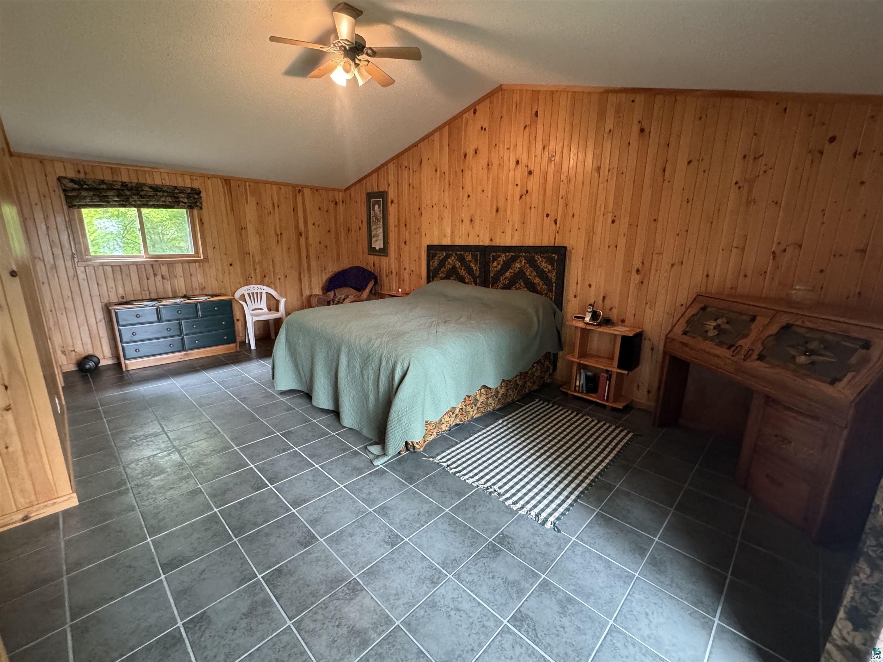 10690 Cedar Crest Road Iron River, WI 54847 - Photo 15 of 24 Tiled bedroom featuring lofted ceiling, wooden walls, and ceiling fan, and attached bathroom