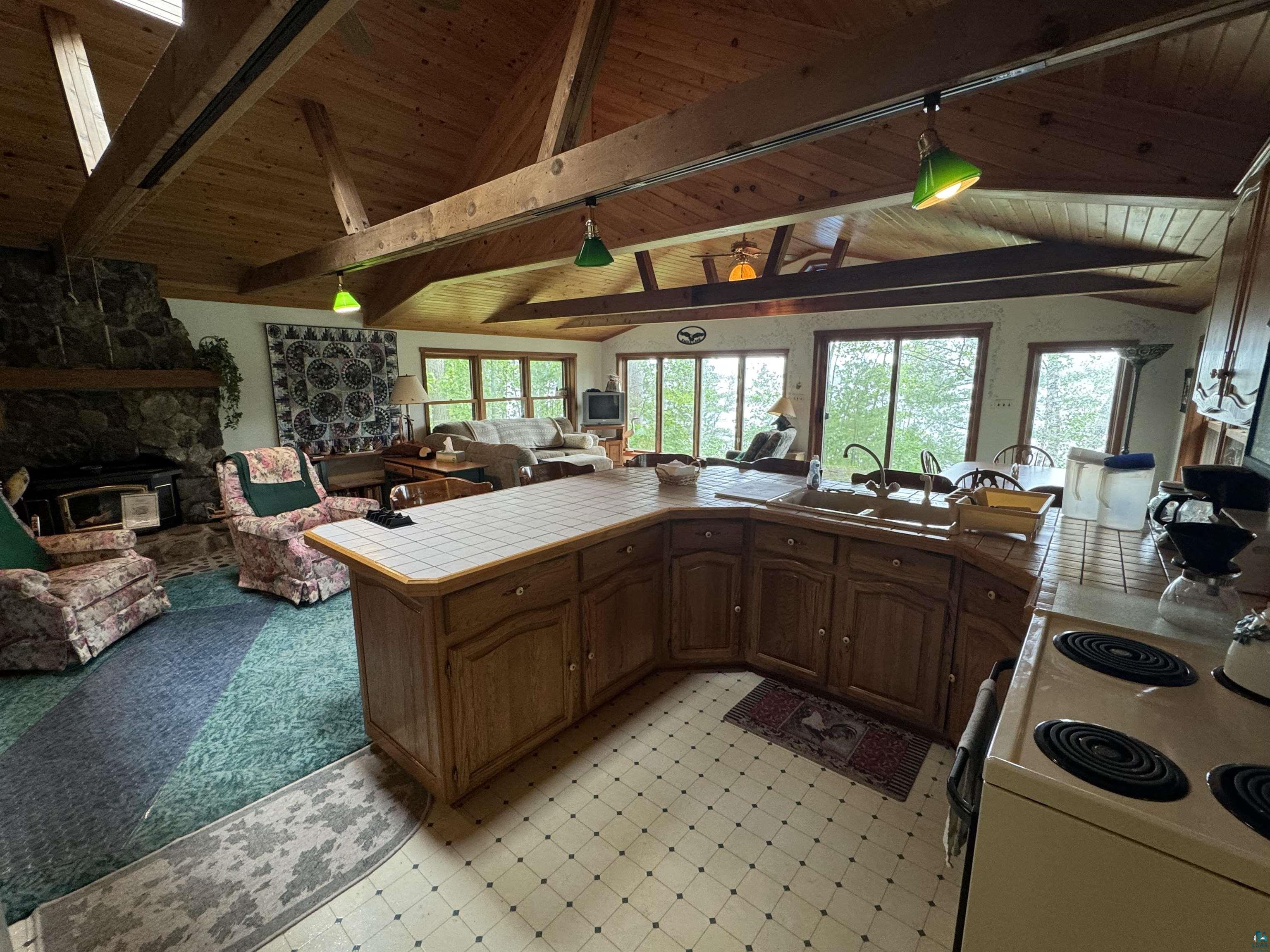 10690 Cedar Crest Road Iron River, WI 54847 - Photo 5 of 24 Kitchen featuring vaulted ceiling with beams, a fireplace, wood ceiling, and stove