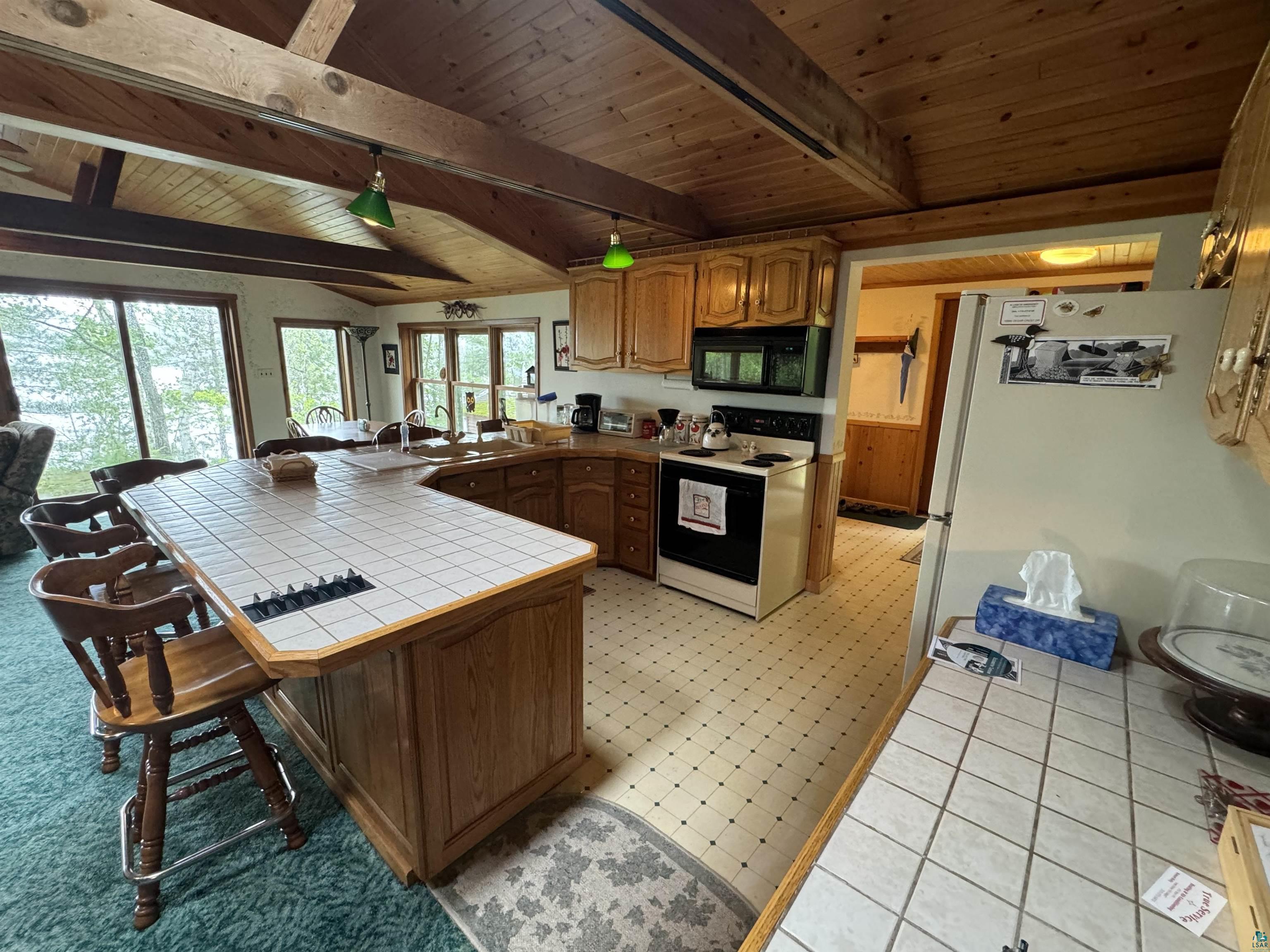 10690 Cedar Crest Road Iron River, WI 54847 - Photo 6 of 24 Kitchen featuring white appliances, tile countertops, beam ceiling, wood ceiling, and light tile floors