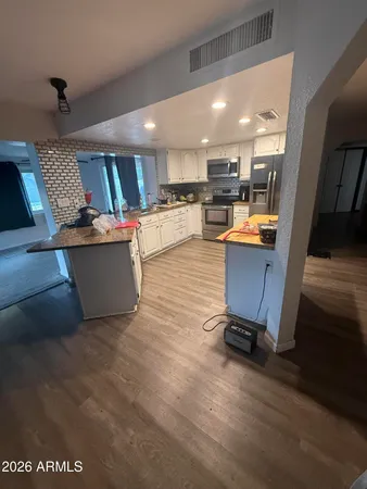 a view of kitchen with kitchen island wooden floors appliances and furniture