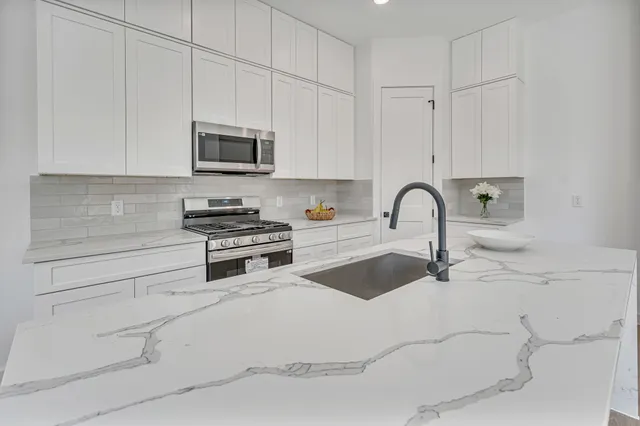 a kitchen with stainless steel appliances granite countertop a stove a sink and a white cabinets