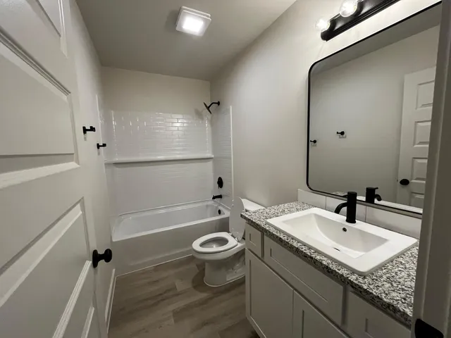 a bathroom with a granite countertop sink a toilet and shower
