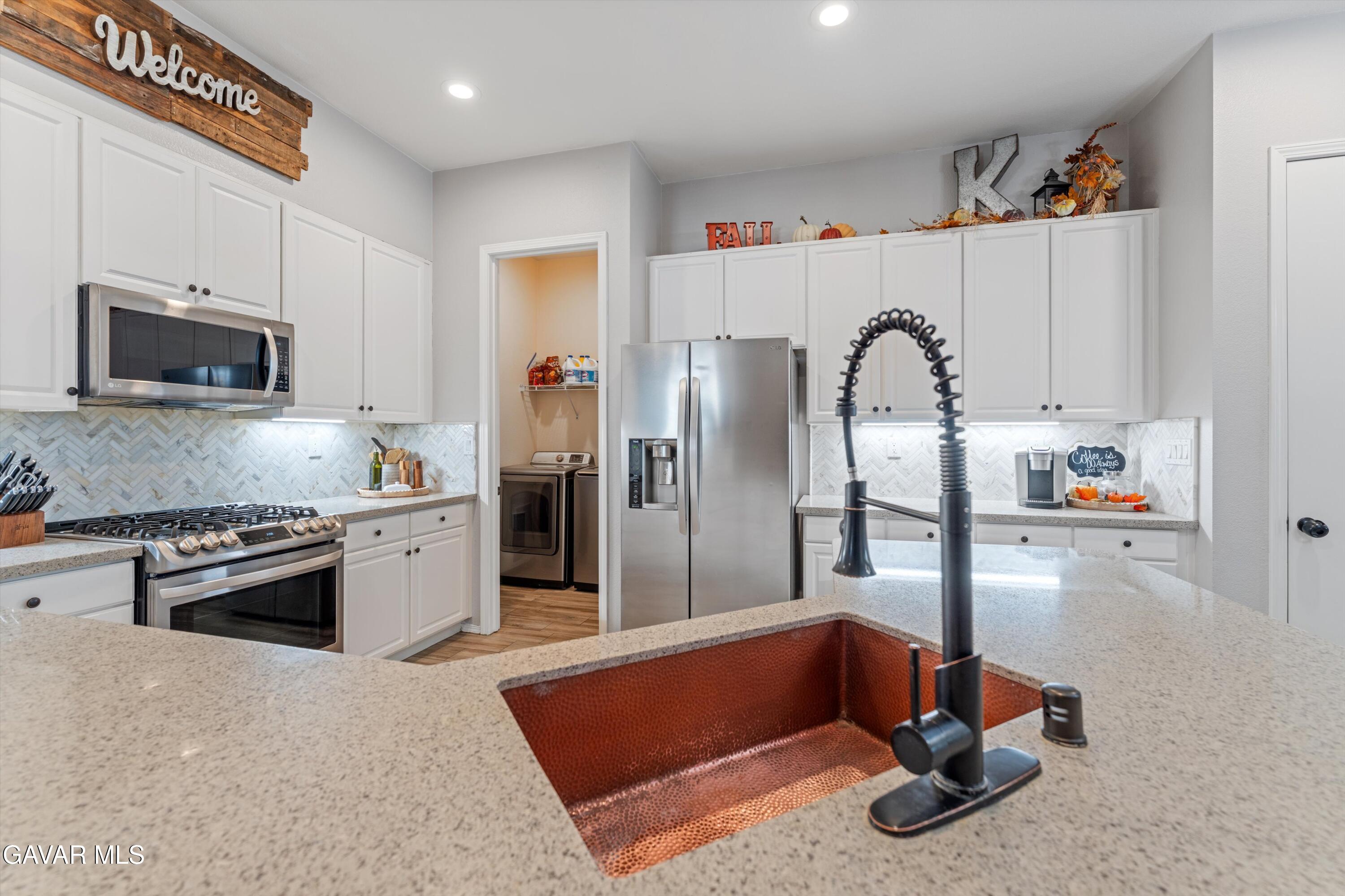 1413 Wild Olive Road Tehachapi, CA 93561 - Photo 24 of 29 a kitchen with stainless steel appliances granite countertop a refrigerator oven a sink dishwasher and white cabinets with wooden floor