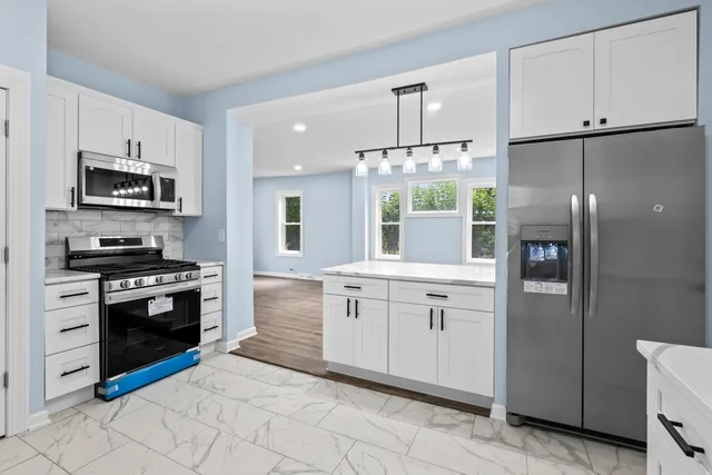 a kitchen with stainless steel appliances granite countertop a refrigerator a stove and a sink