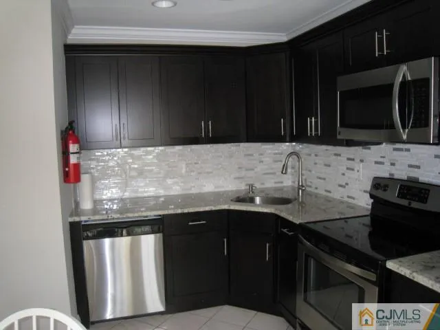 a kitchen with granite countertop stainless steel appliances a sink dishwasher a stove microwave and cabinets