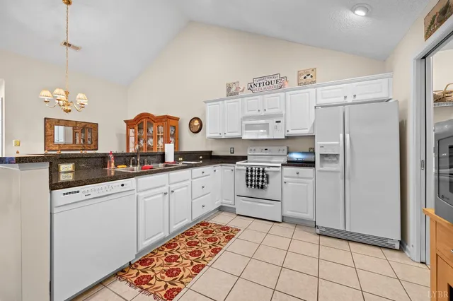 a kitchen with granite countertop a white stove top oven and cabinets
