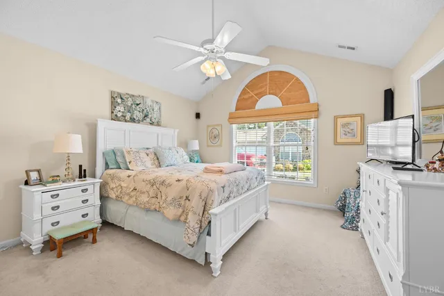 a spacious bedroom with a bed a dresser and a large window