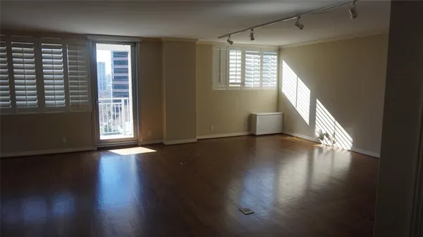 an empty room with wooden floor and windows with curtains