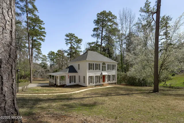 a front view of a house with a garden and trees