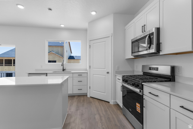 1355 West 2350 South, Unit 11 Perry, UT 84302 - Photo 4 of 39 Bright kitchen featuring white cabinetry, light-toned countertops, and wood-finish flooring