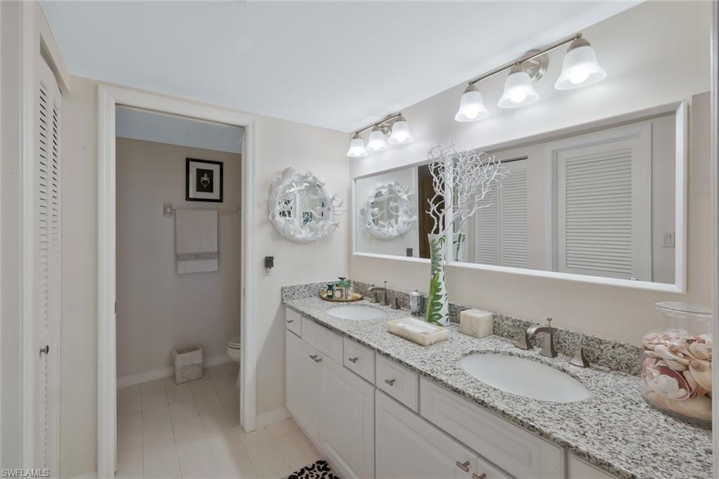 6573 Marissa Loop, Unit 303 Naples, FL 34108 - Photo 13 of 31 a bathroom with a granite countertop sink mirror and toilet