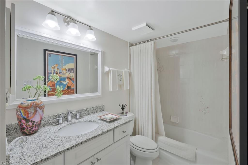 6573 Marissa Loop, Unit 303 Naples, FL 34108 - Photo 15 of 31 a bathroom with a granite countertop sink a toilet a shower and a mirror